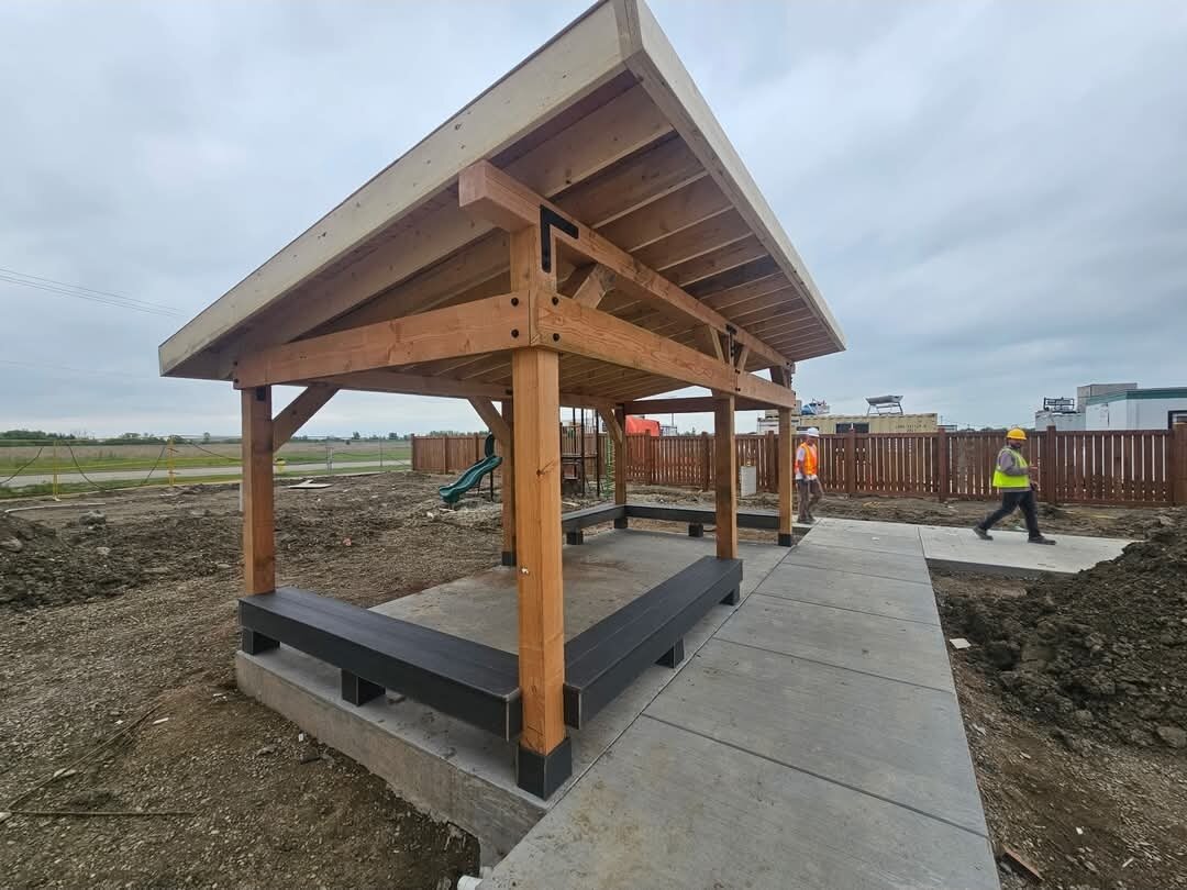 Bravo Builders — Completed timber-frame outdoor shelter with bench seating