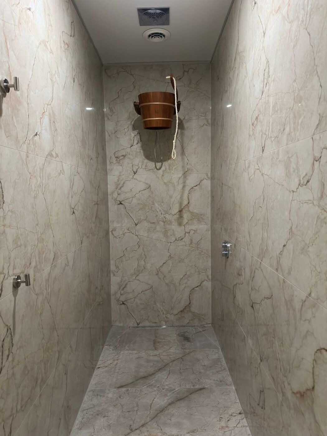 Gosur Development Inc. — Marble-tiled shower room with cold-water bucket