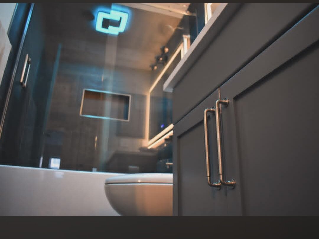 Harvest Pro Renovations — Renovated bathroom with backlit mirror and custom vanity