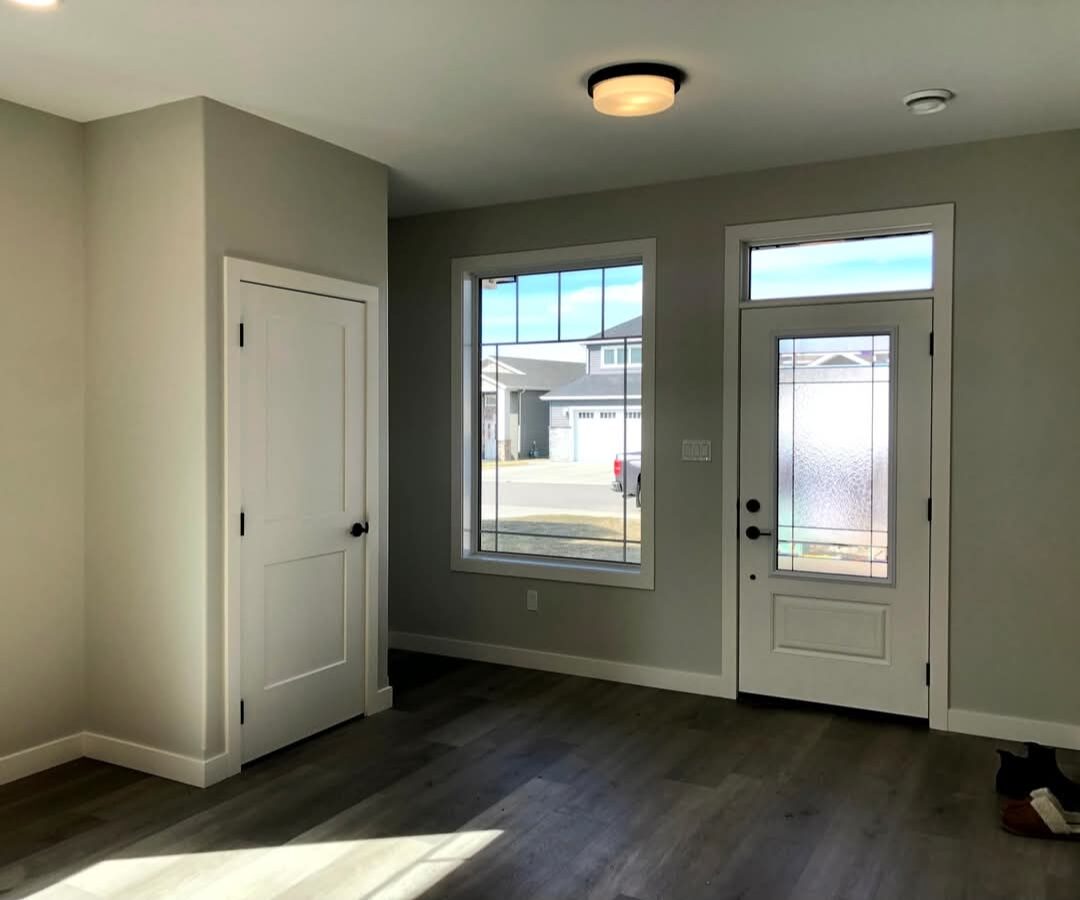 Genica Custom Builders — Bright new-home entryway with glass front door